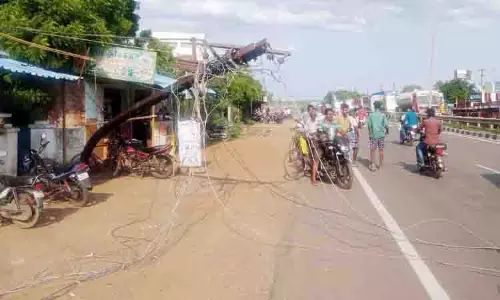 லாரி டிப்பரில் மின்கம்பிகள் சிக்கியதால் சாலையில் சாய்ந்த கம்பம்