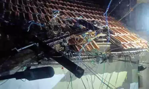 வீட்டின் மீது விழுந்த மின்கம்பம்