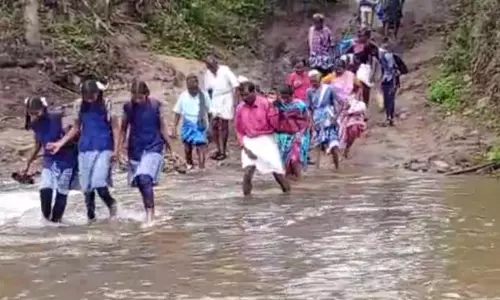கடம்பூர் அருகே சேறு, சகதி காரணமாக காட்டாற்றை பஸ் கடக்க முடியாததால் போக்குவரத்து பாதிப்பு- ஆபத்தை உணராமல் வெள்ளத்தை கடந்து செல்லும் மாணவ, மாணவிகள்
