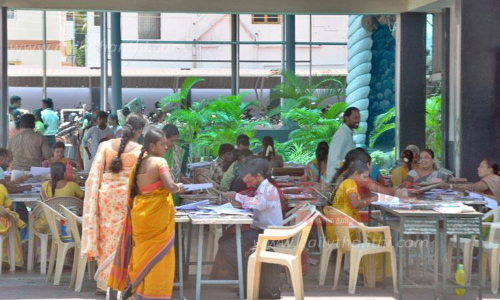 பள்ளி வராண்டாவில் அமர்ந்து விடைத்தாள் திருத்திய ஆசிரியர்கள்