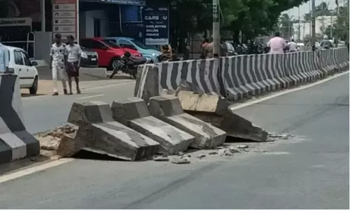 சாலையில் நடுவே விழுந்து கிடக்கும் கான்கிரீட் தடுப்பு