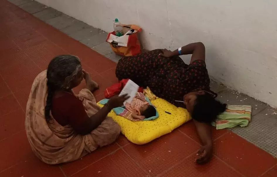 படுக்கை வசதி இல்லாததால் பச்சிளங்குழந்தையுடன் தரையில் படுத்த பெண்