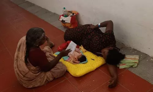 படுக்கை வசதி இல்லாததால் பச்சிளங்குழந்தையுடன் தரையில் படுத்த பெண்