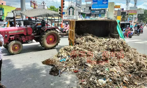 வளைவில் திரும்பும் போது டிராக்டர் கவிழ்ந்தது:சாலையில் குப்பைகள் கொட்டியதால் பரபரப்பு