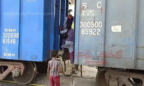 சரக்கு ரெயில் பெட்டிகளுக்கு நடுவில் நின்று பள்ளிக்கு சென்ற மாணவிகள்