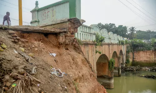இடிந்து விழும் நிலையில் பாலத்தின் பக்கவாட்டு சுவர்